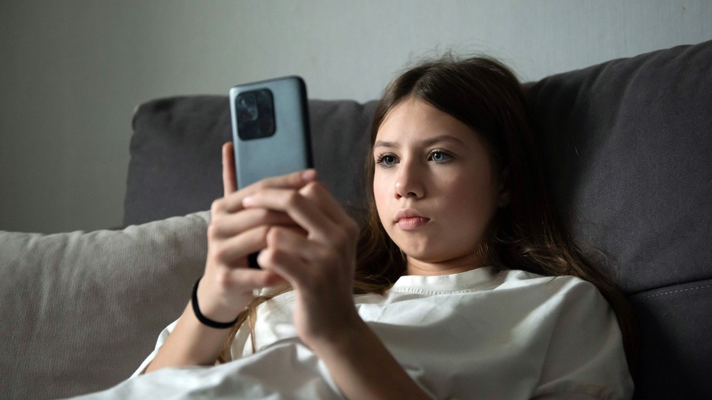 Ein Kind sitzt mit Smartphone auf der Couch