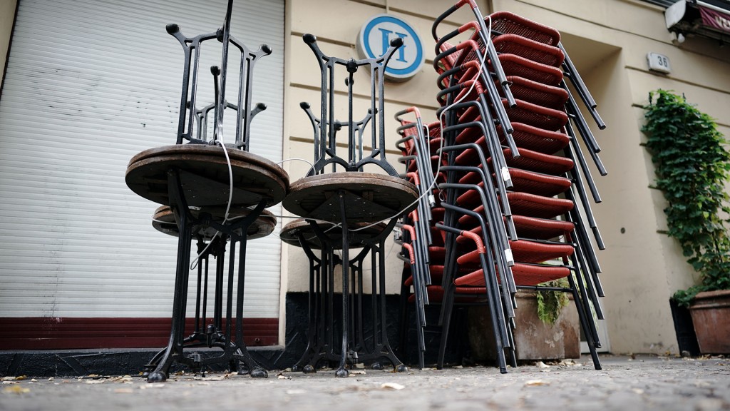 Gestapelte Tische und Stühle stehen vor einem Lokal