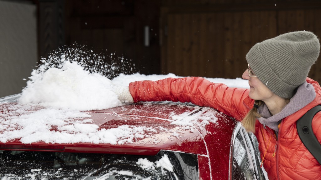 Eine Frau fegt den Schnee von ihrem Auto
