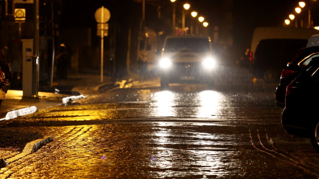 Symbolbild: Die Scheinwerfer eines Autos spiegeln sich auf einer teilweise vereisten Straße. 