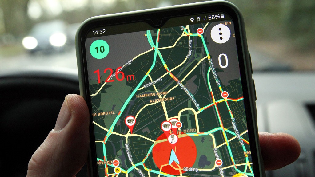 Jemand hält im Auto ein Smartphone in der Hand, auf dem eine Blitzer-Warn-App geöffnet ist