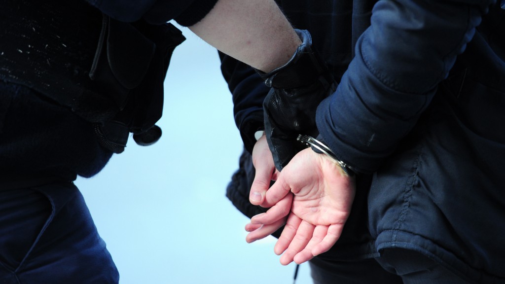 Ein Polizist legt einem Verdächtigen Handschellen an