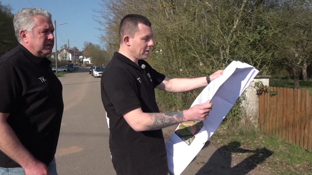 Foto: Verantwortliche schauen in Pläne vor Baugrundstück