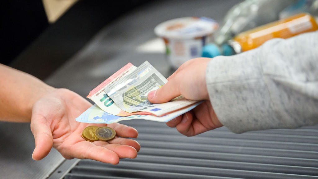 Eine Kassiererin gibt einer Kundin Wechselgeld an der Kasse eines Supermarktes