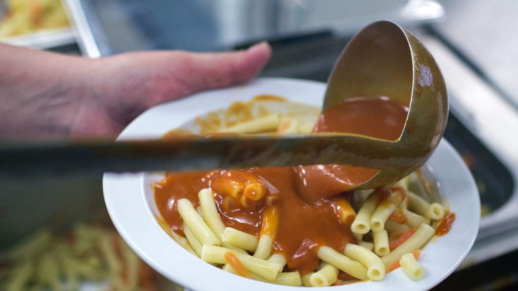 Mit einer Kelle wird das Essen auf Teller verteilt.
