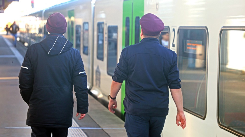 Foto: Zwei Bahnmitarbeiter gehen einen Bahnsteig entlang.