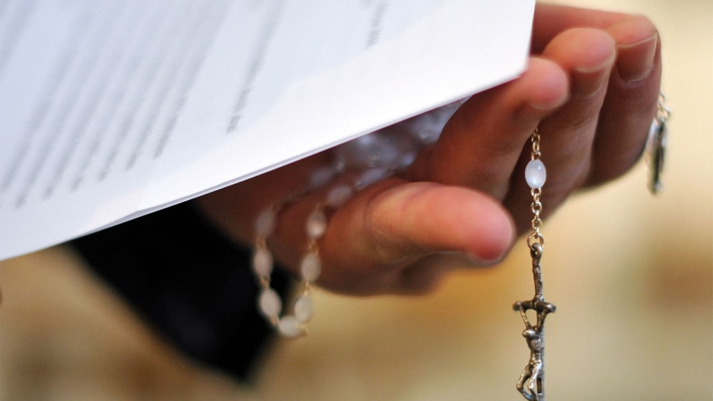 Ein Priester hält einen Rosenkranz und Papier in der Hand