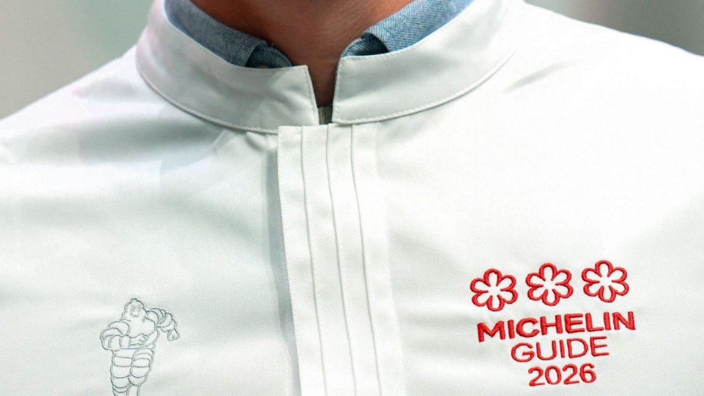Ein Koch mit dem Logo des Michelin Guide 2026 und drei Sternen auf seiner Jacke