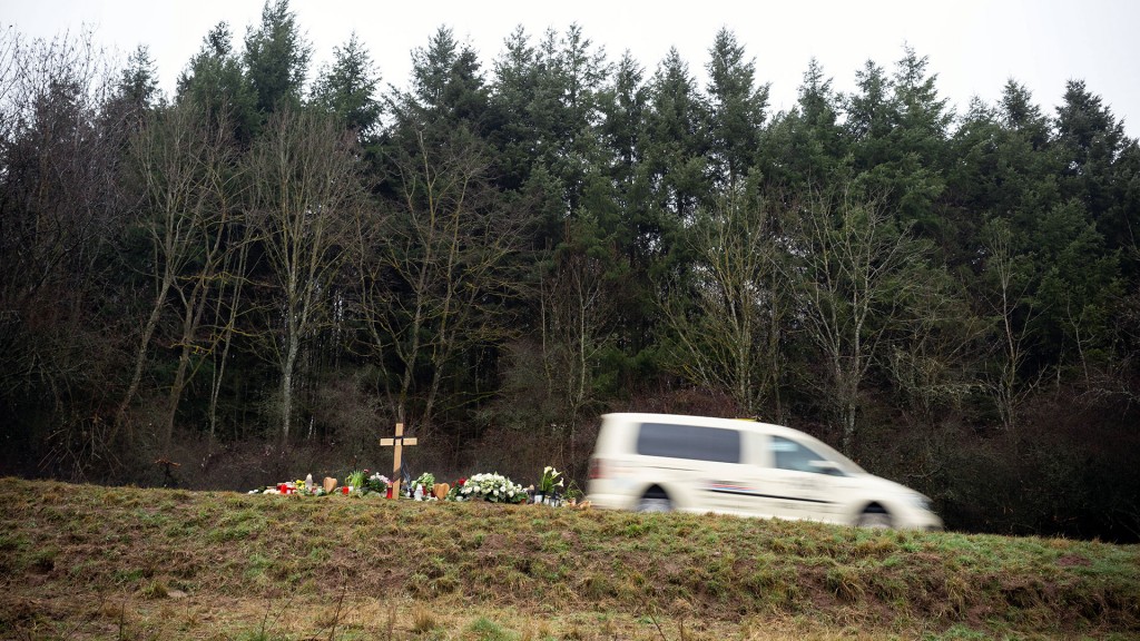 Blumen und ein Kreuz stehen zum Gedenken am Tatort des Polizistenmordes bei Kusel