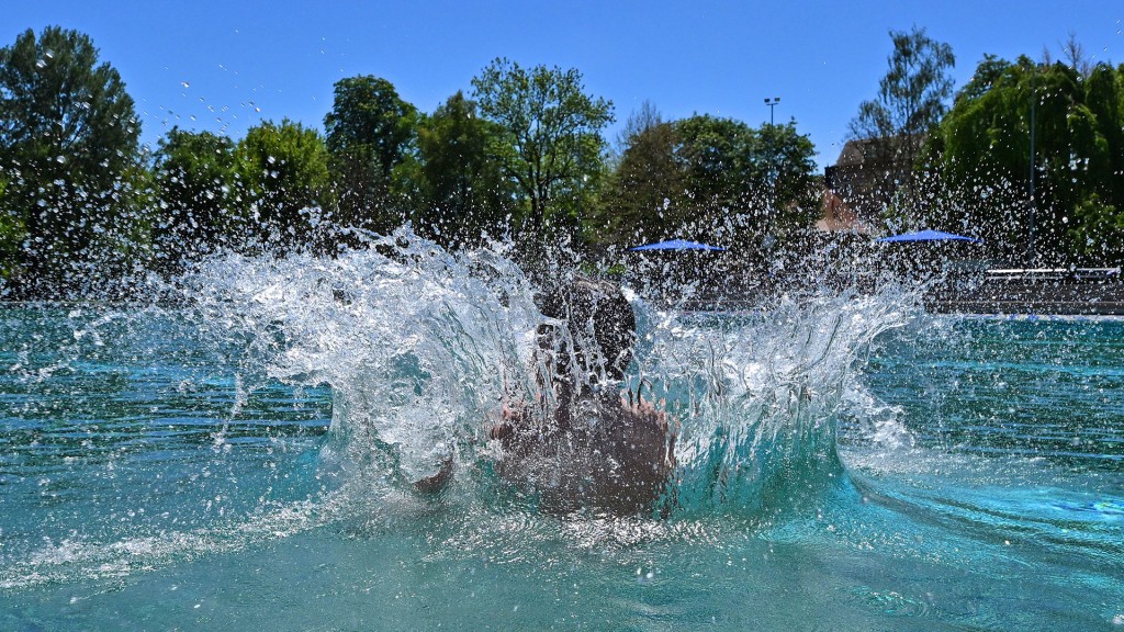 Ein Kind springt im Freibad ins Wasser 