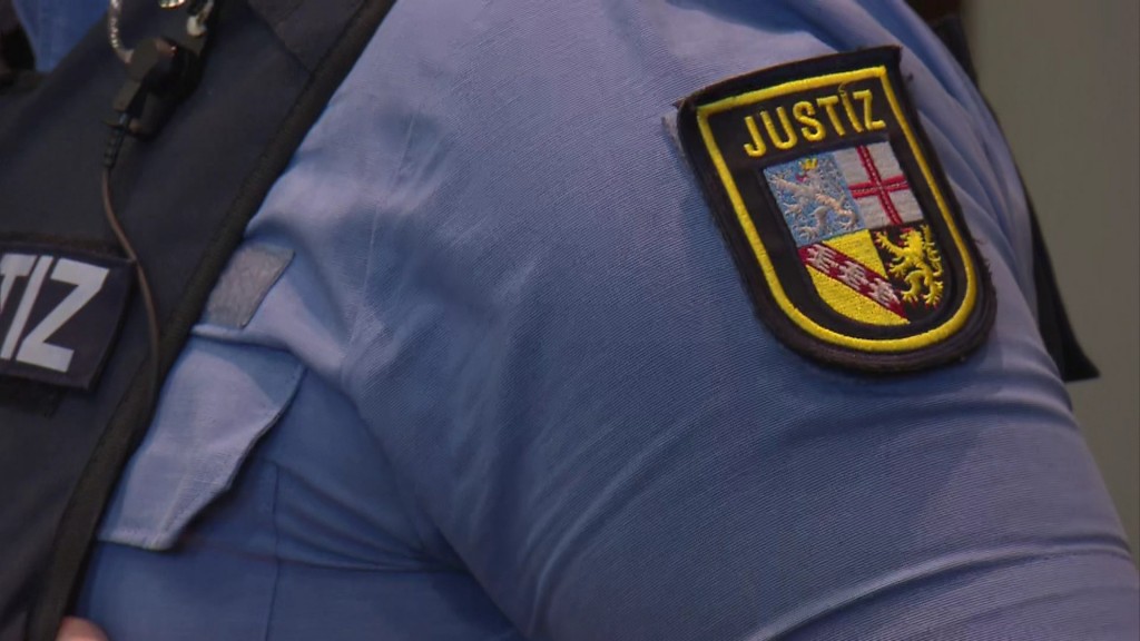 Das Abzeichen der saarländischen Justiz auf dem Hemd eines Justizbeamten.