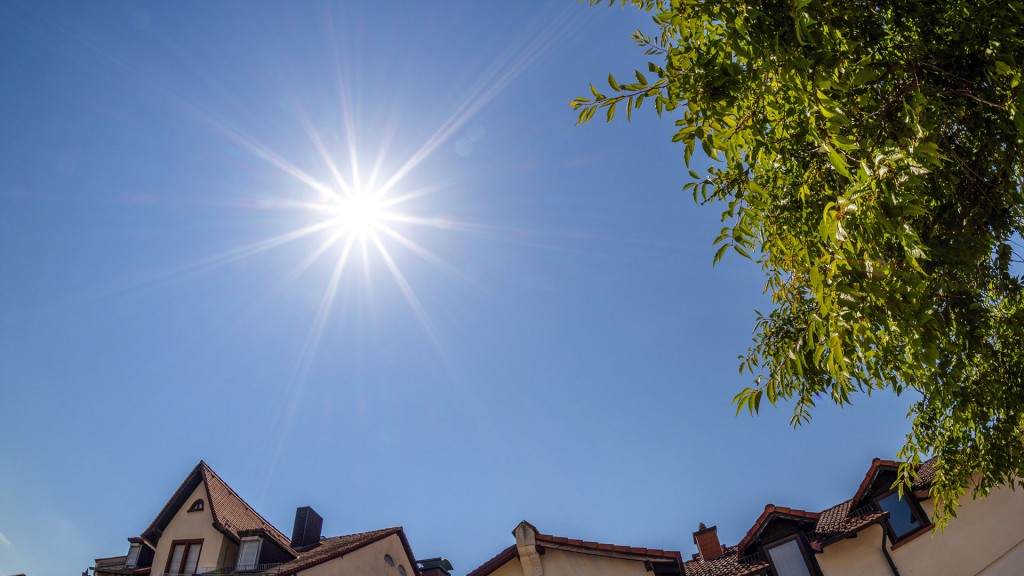 Die Sonne steht hoch über Wohnhäusern am wolkenfreien Himmel