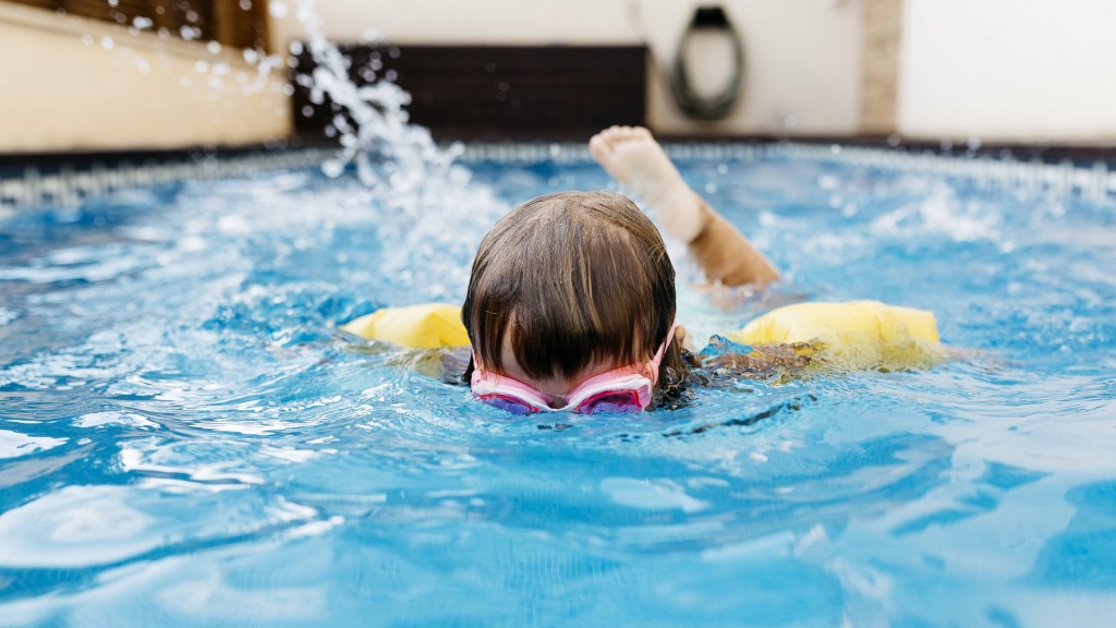 Ein Mädchen mit Schwimmbrille und Schwimmflügeln in einem Schwimmbecken