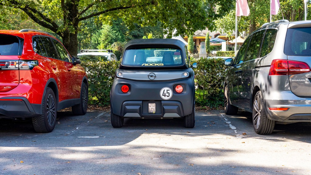 Foto: Ein Microcar parkt zwischen zwei großen Pkw