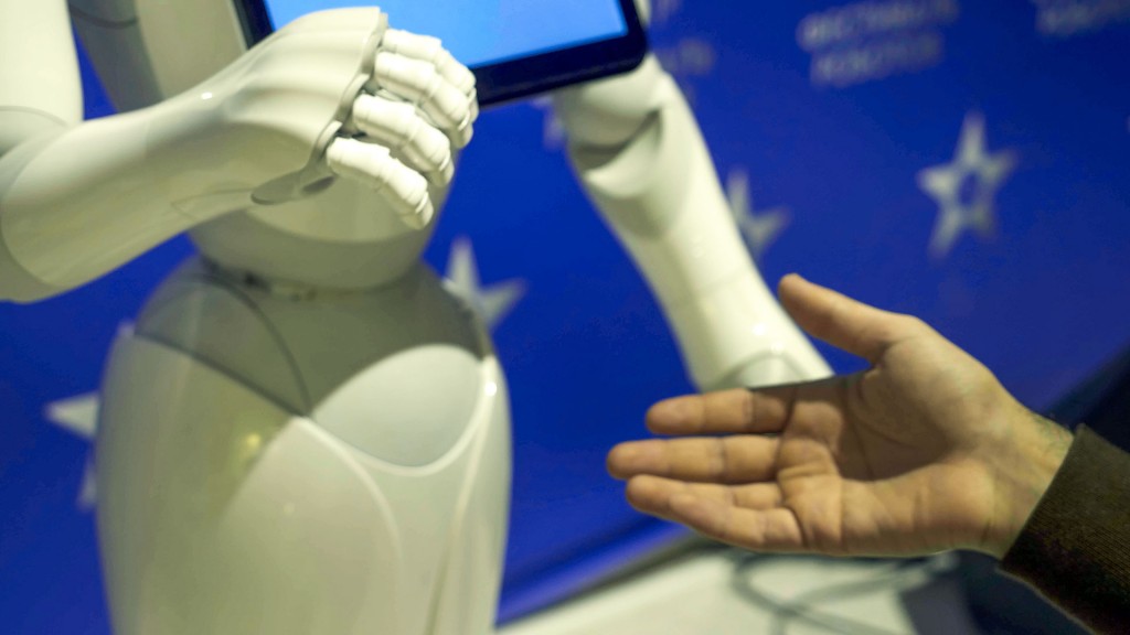 Foto: Symbolbild: Ein Roboter und ein Mensch reichen sich die Hände