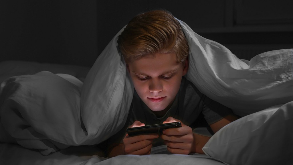 Teenager mit Smartphone im Bett